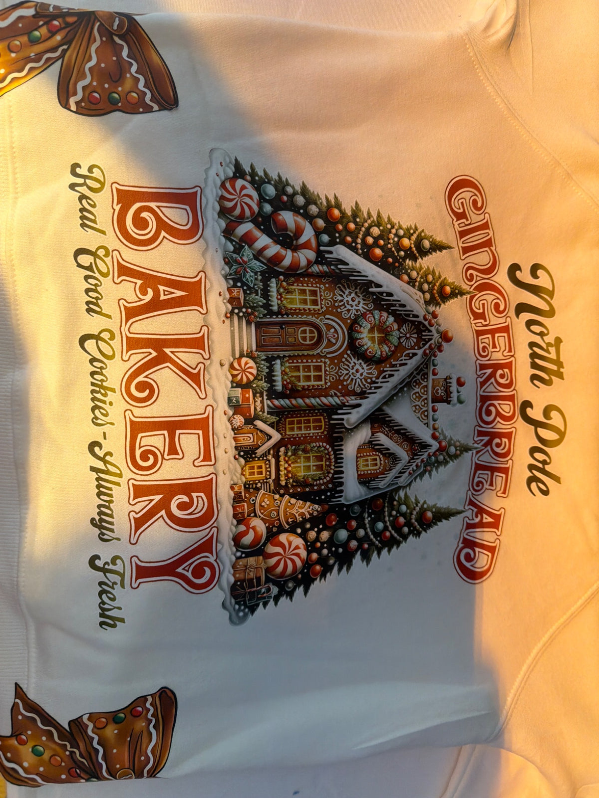 Close-up of gingerbread bakery DTF transfer detail on a cream sweatshirt; finished application example.